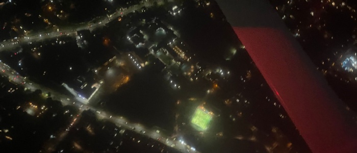 Arial photo of OSH site at night lit up with street lights, clearly showing boarding houses and sports pitches